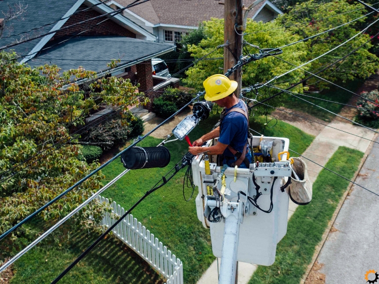 Elektryk pracujący na podnośniku przy montażu przewodów napowietrznych