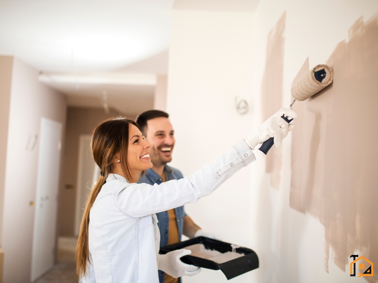 Para malująca wspólnie ścianę w nowym mieszkaniu